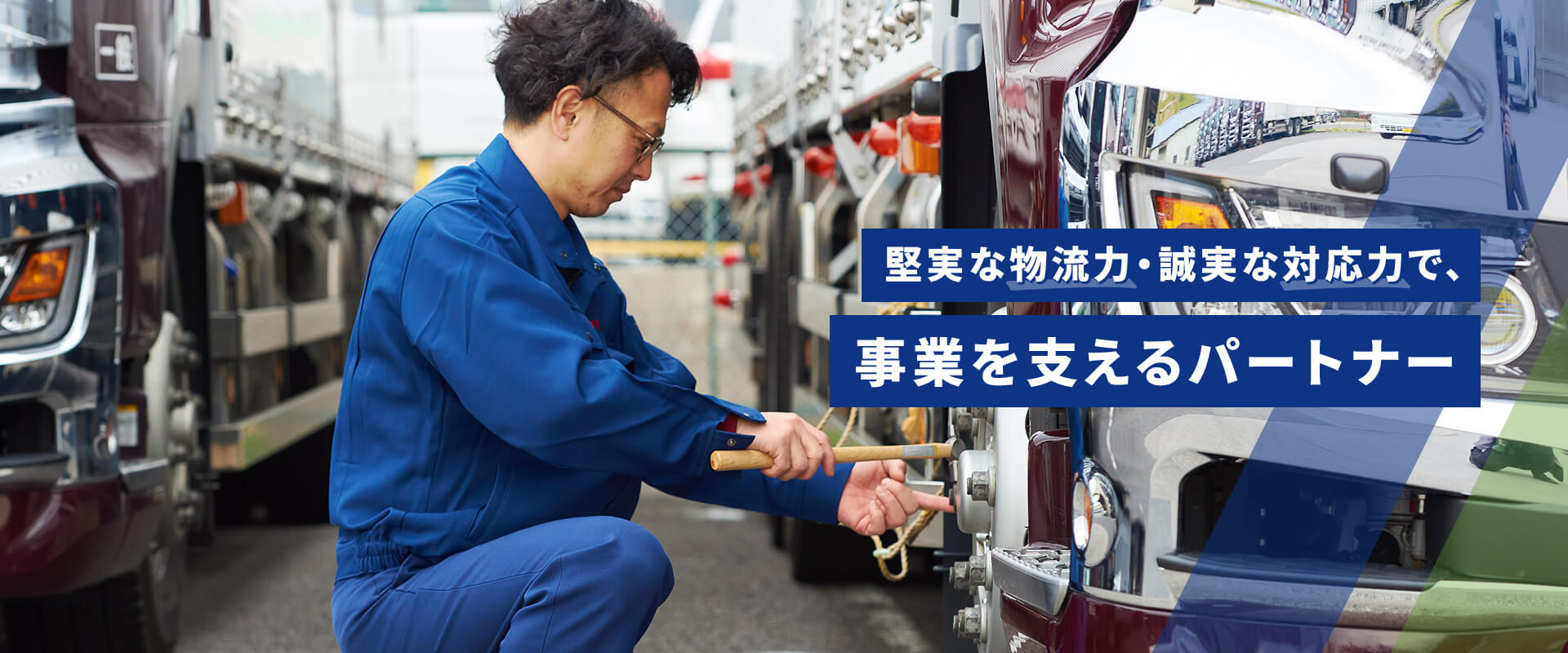 堅実な物流力・誠実な対応力で、事業を支えるパートナー トラックのタイヤを点検する人物の写真